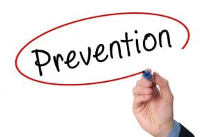 The word prevention is drawn in black ink, and a man's hand holding a marker has just circled the word in red ink. 